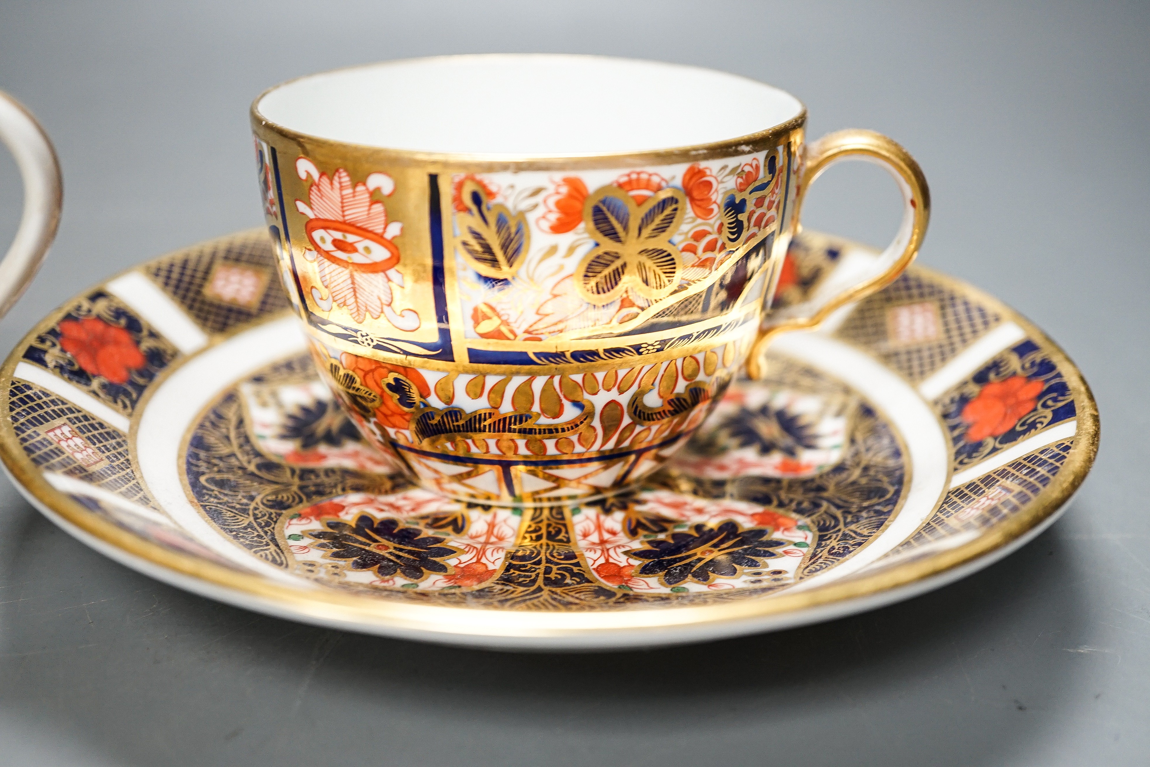 A Derby Imari saucer, a similar tea cup, a pair of Sampson Hancock, Derby figures, and a Derby cup, tallest figure 13 cms high.